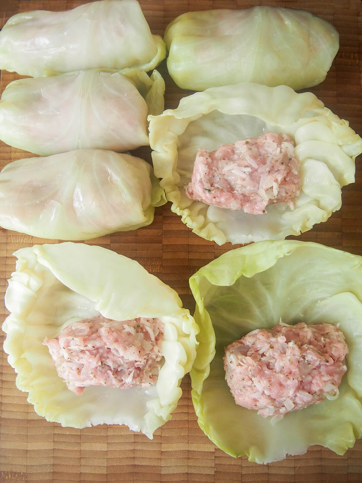 some rolled up cabbage rolls and leaves with filling on top before they are rolled.