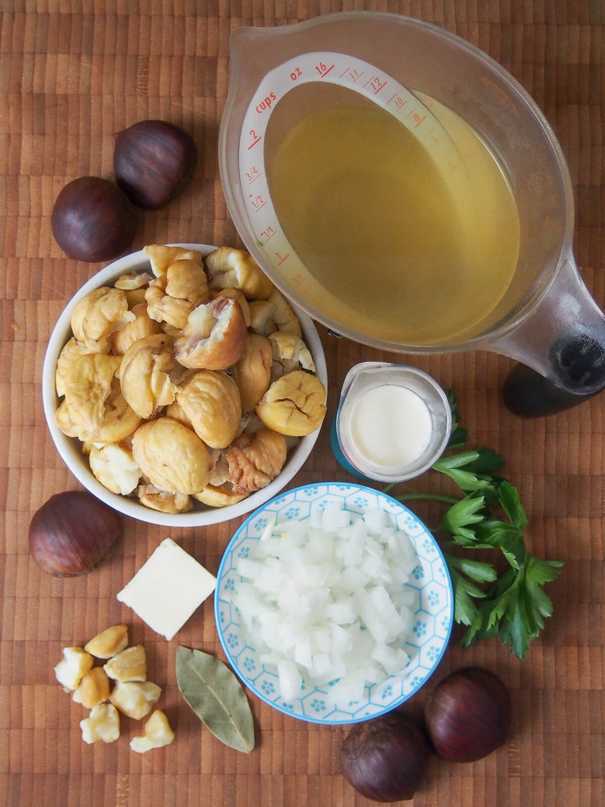 overhead view of bowls with chestnuts and chopped onion and measures with cream and stock.