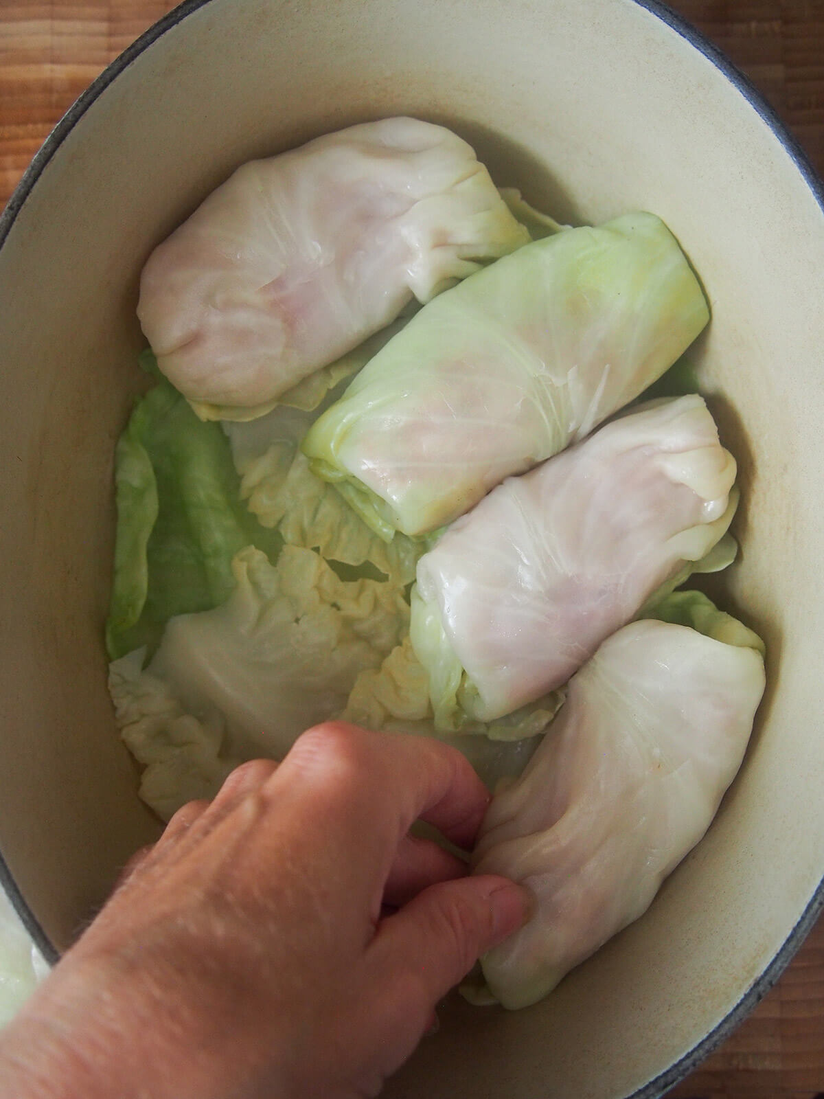 placing formed Polish stuffed cabbage rolls in pot with spare leaves in the bottom of the pot
