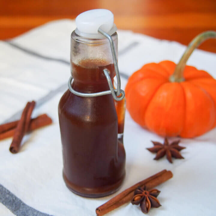 bottle of homemade pumpkin spice syrup with mini pumpkin behind