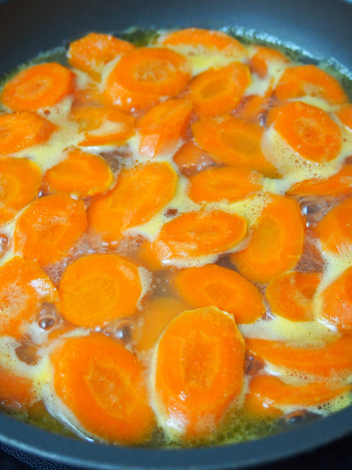 carrots simmering in water with butter in it.