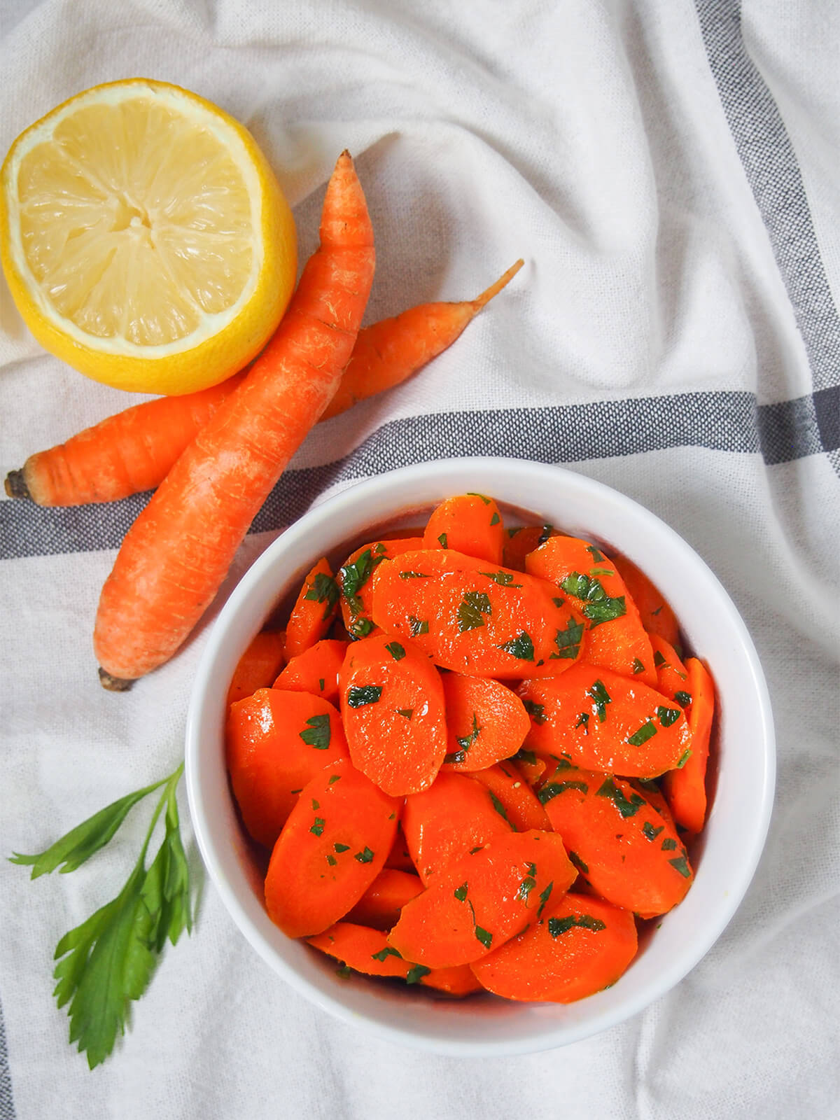 bowl of vichy carrots from overhead with carrots and lemon above bowl.
