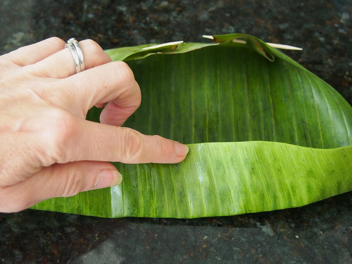 folding a banana leaf to make banana leaf steamer.