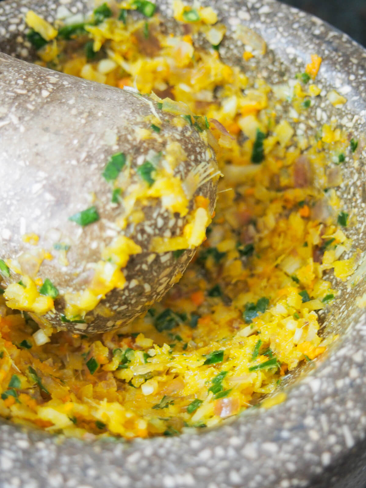 crushing ingredients for spice paste with pestle and mortar.