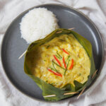 overhead view of fish amok (amok trey) on plate with rice on side of plate.