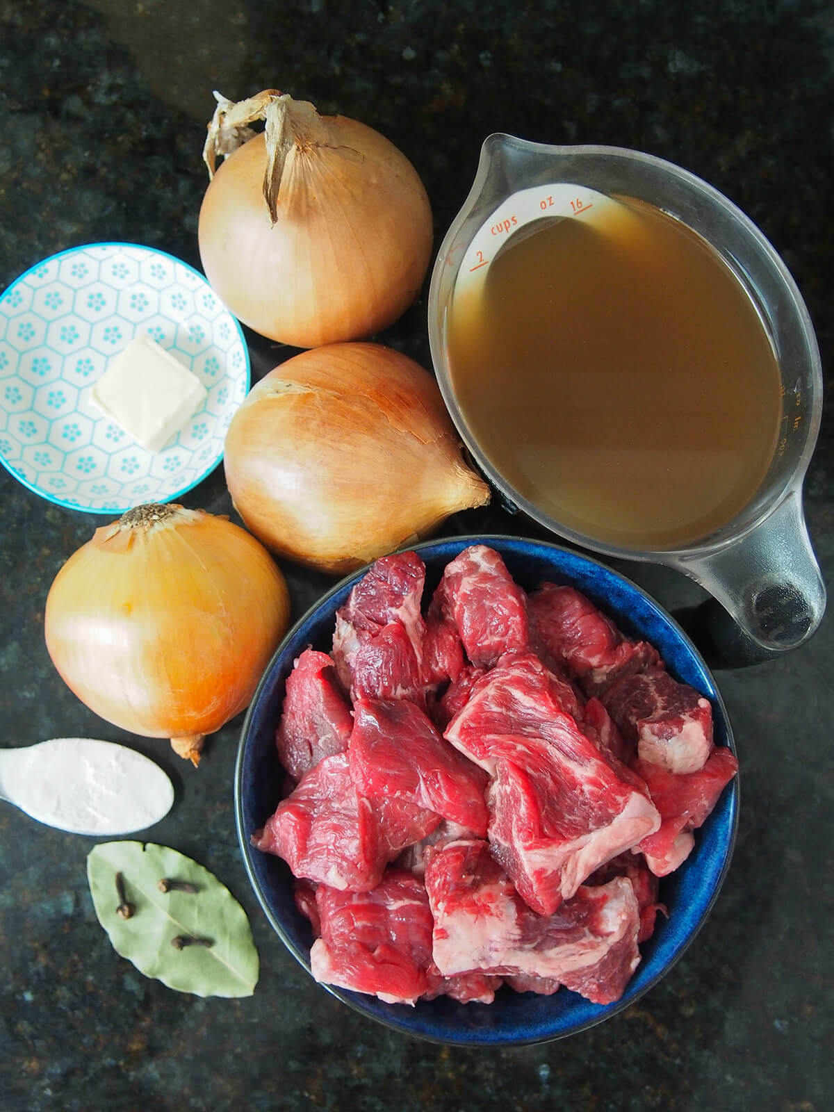 bowl of diced beef, onions, butter, flour, cloves, bay leaf and measure of beef stock.