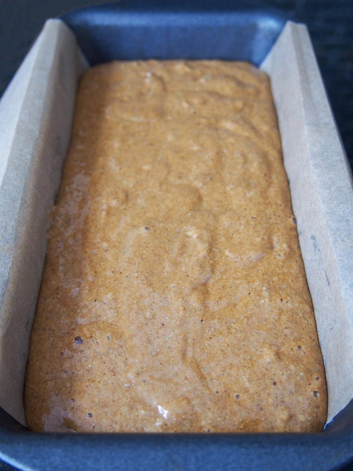 brown colored batter in lined loaf tin