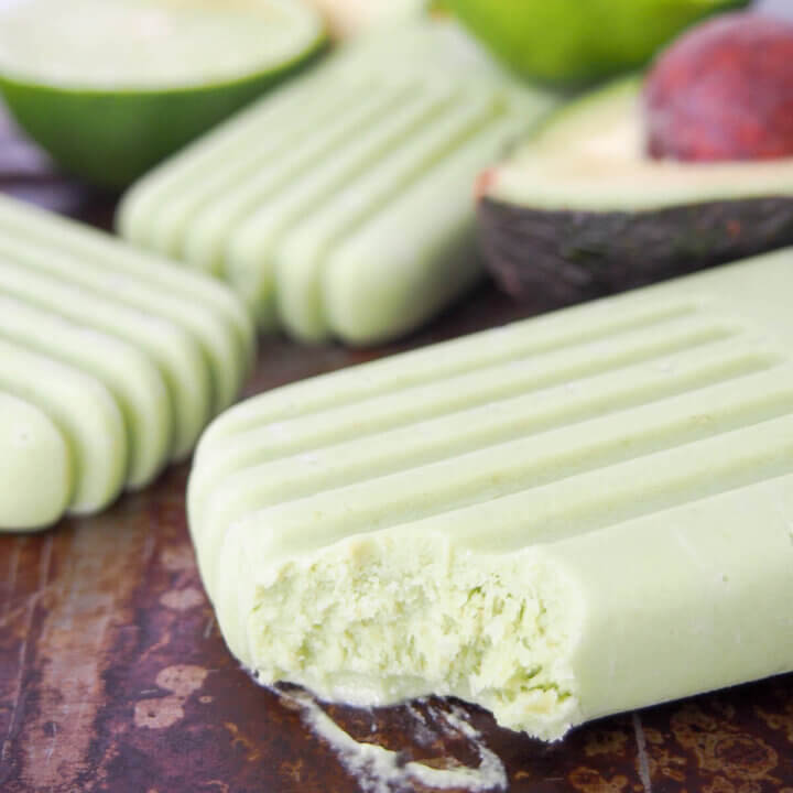 avocado paletas with one at front with bite taken from it.
