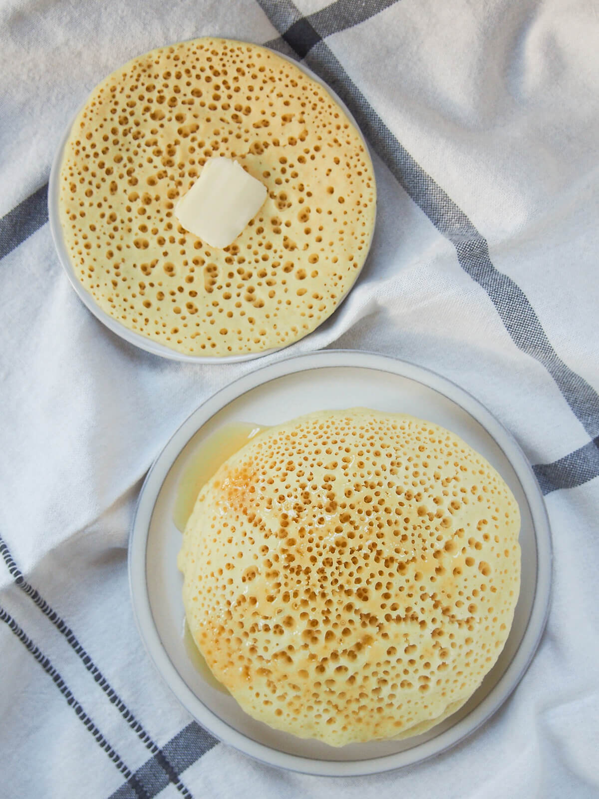baghrir, Moroccan semolina pancakes overhead view of some baghrir, Moroccan pancakes, with one with butter and more with honey over top.