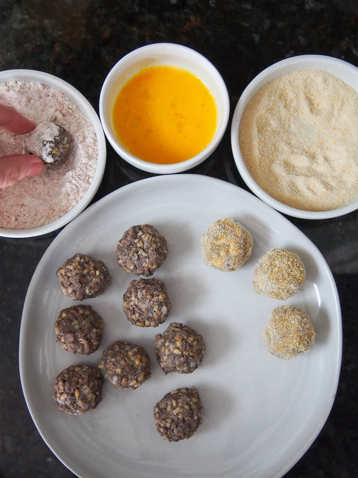 balls of haggis and flour, egg and breadcrumbs in bowls to coat them balls of haggis and bowls with flour, egg, breadcrumbs to roll them in.