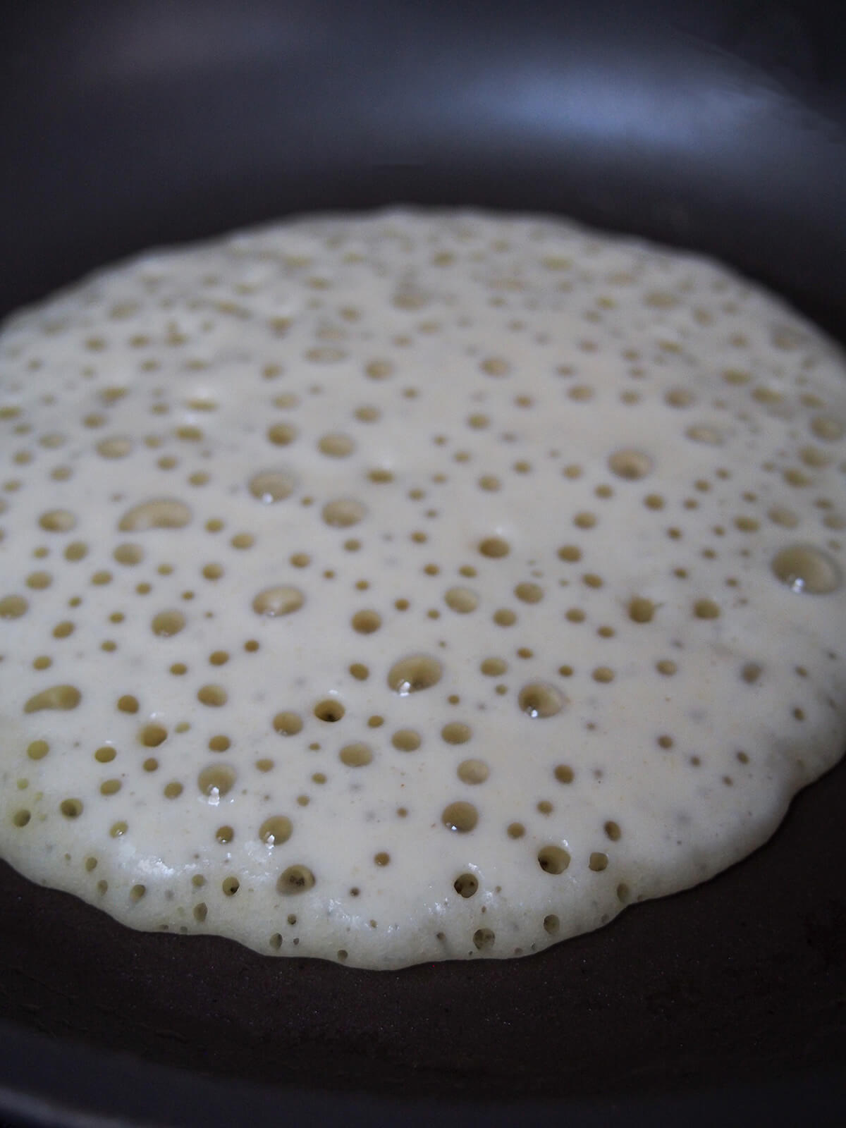 starting to cook baghrir, Moroccan semolina pancakes cooking a Moroccan pancake with lots of air bubbles on top.