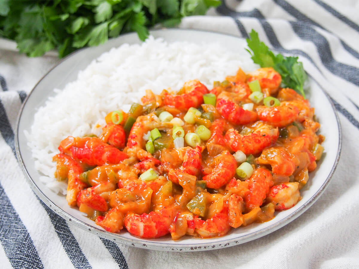 plate with crawfish etouffee at front and rice behind.