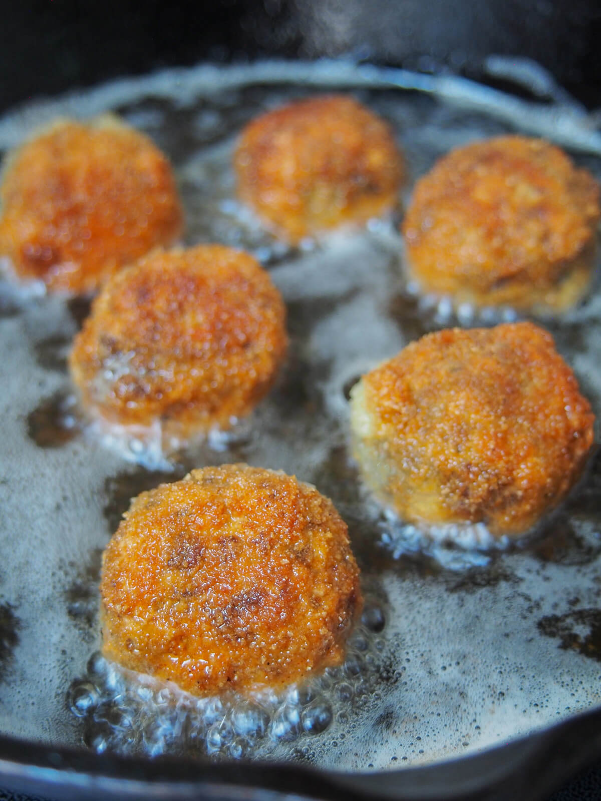 cooking haggis bon bons frying haggis bon bons in skillet with bubbles in the oil.