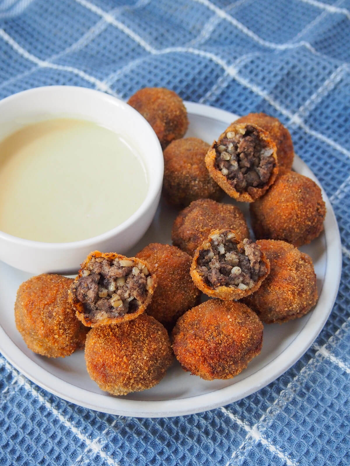 Haggis bon bons are essentially breaded balls of haggis, but the combination of crisp outside and softer, meaty inside makes them a delicious finger food appetizer. Easy & a great haggis introduction. plate of haggis bon bons with mustard mayo to side.