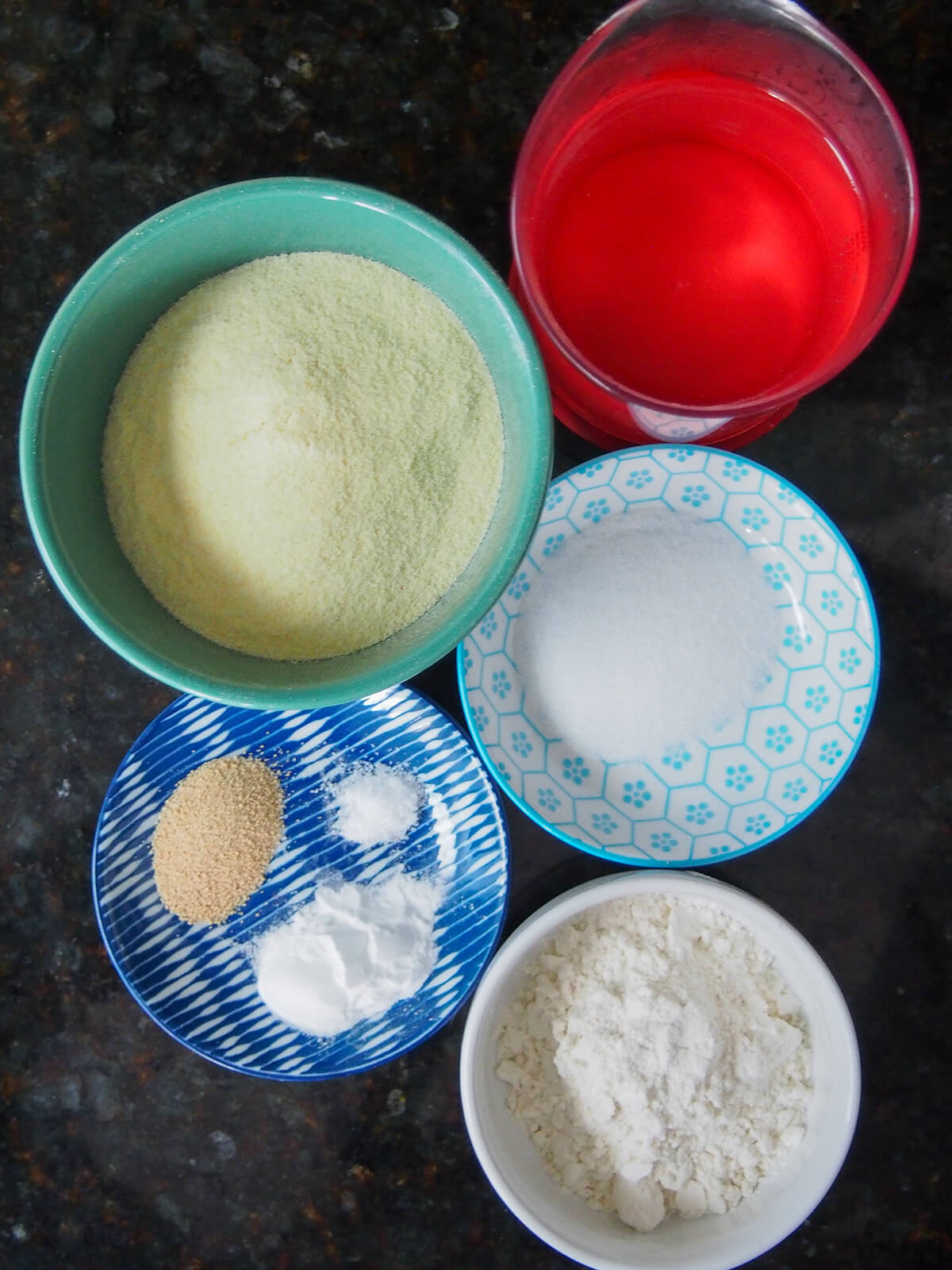 ingredients for baghrir, Moroccan semolina pancakes overhead view of bowls of semolina flour, flour, water, sugar, yeast, salt and baking powder.