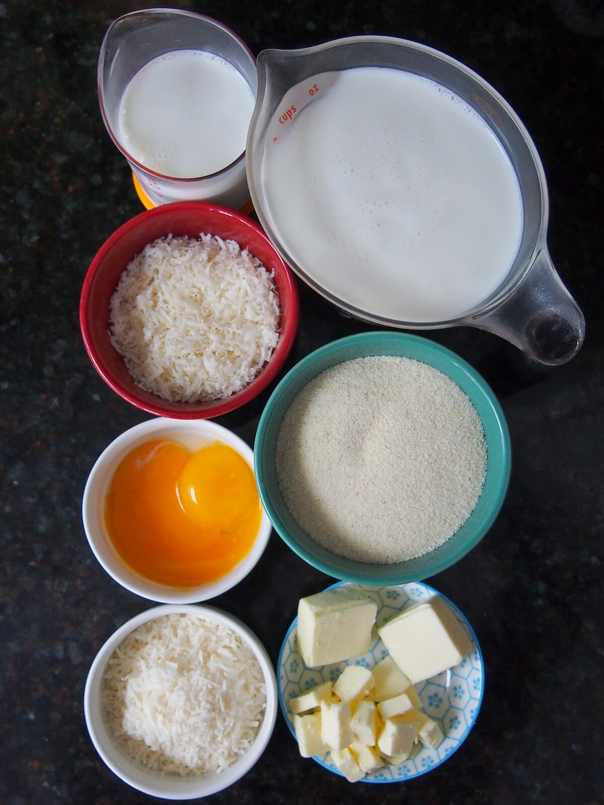 bowls and measures with parmesan, milk, semolina, butter, egg yolks.