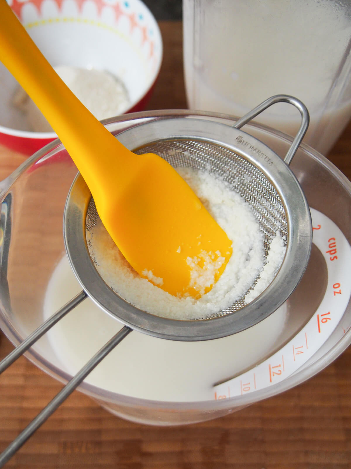 straining almond milk mixture to hold back almond solids in fine strainer.