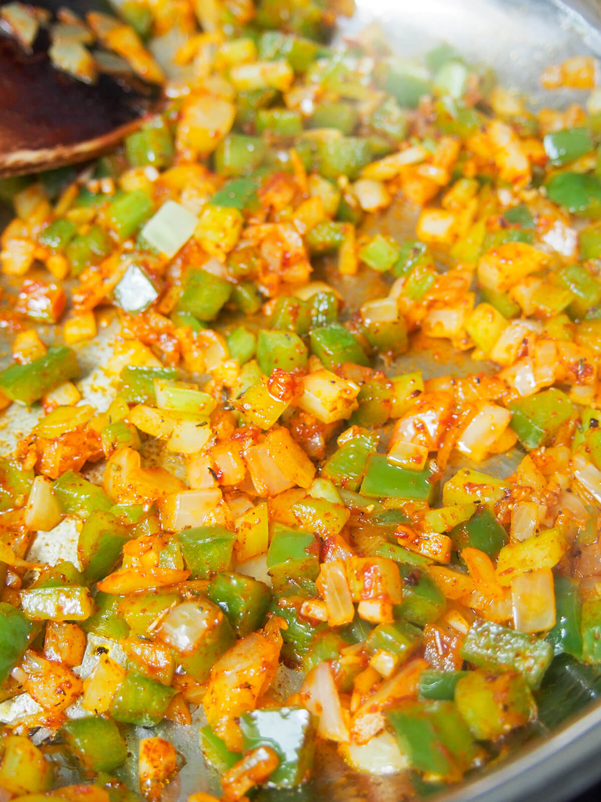 cooked diced vegetables with spices mixed through them in pan.