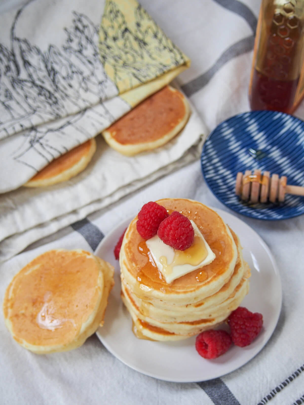 overhead view of stack of Scotch pancakes, aka drop scones, with more under cloth behind.