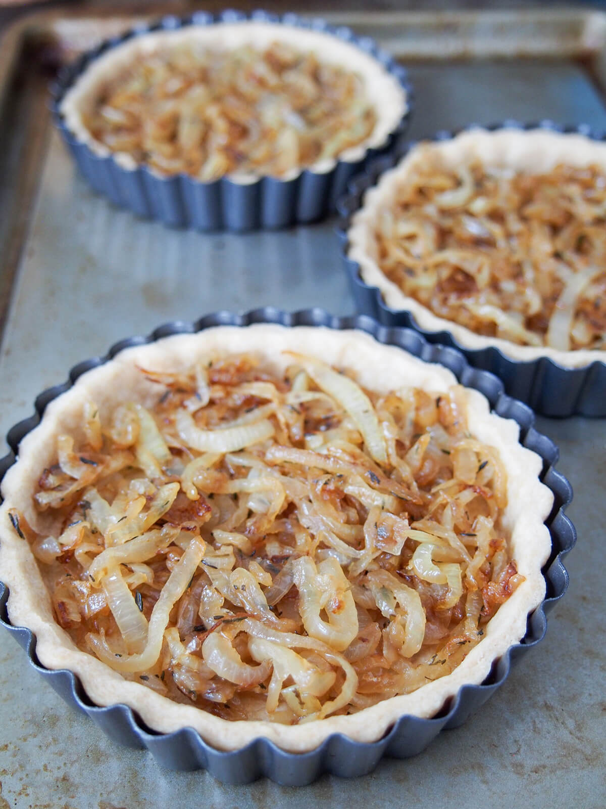caramelized onions in the bottom of pastry crusts on baking sheet.