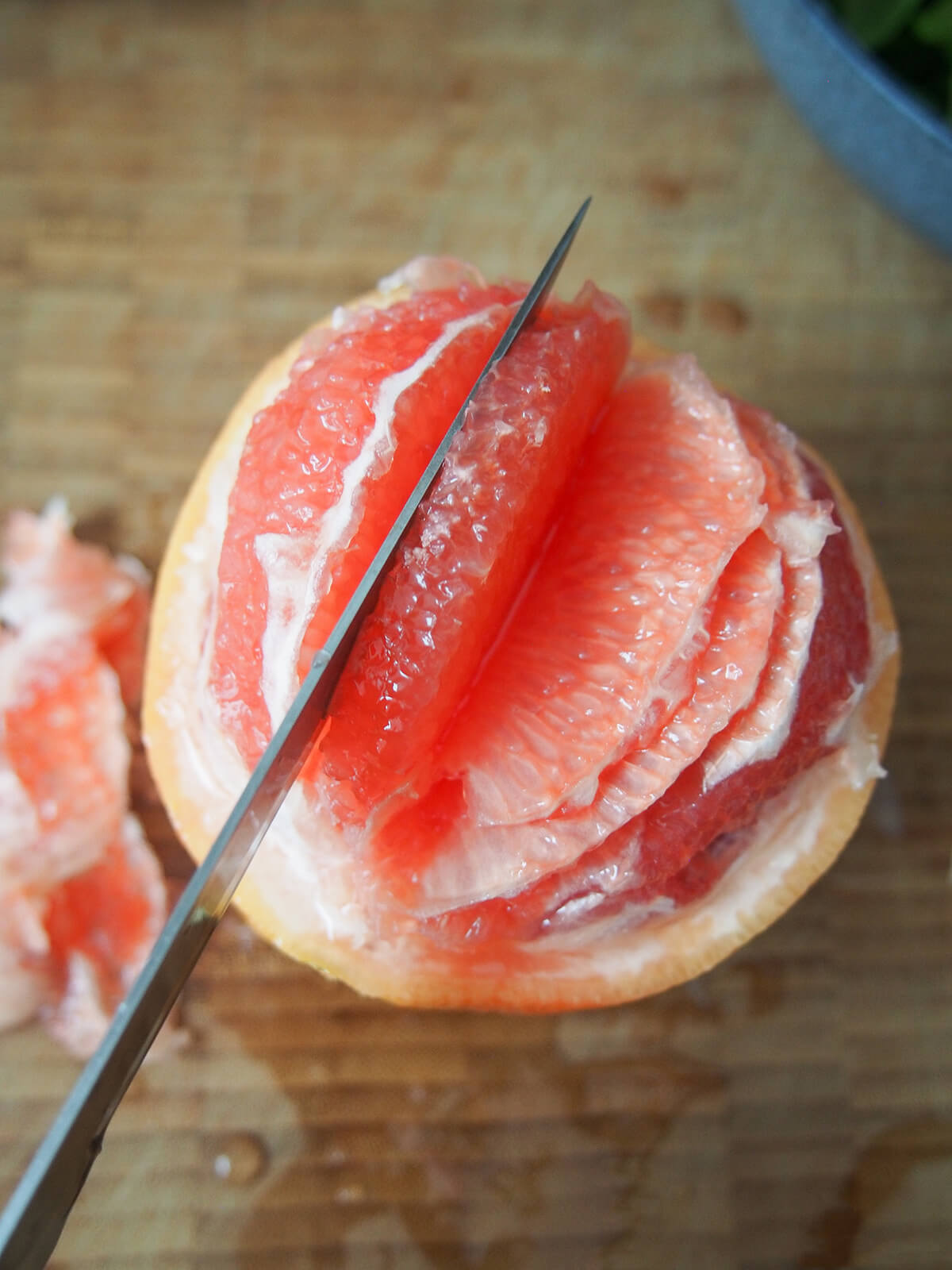 cutting segment from a grapefruit showing knife cutting near membrane.