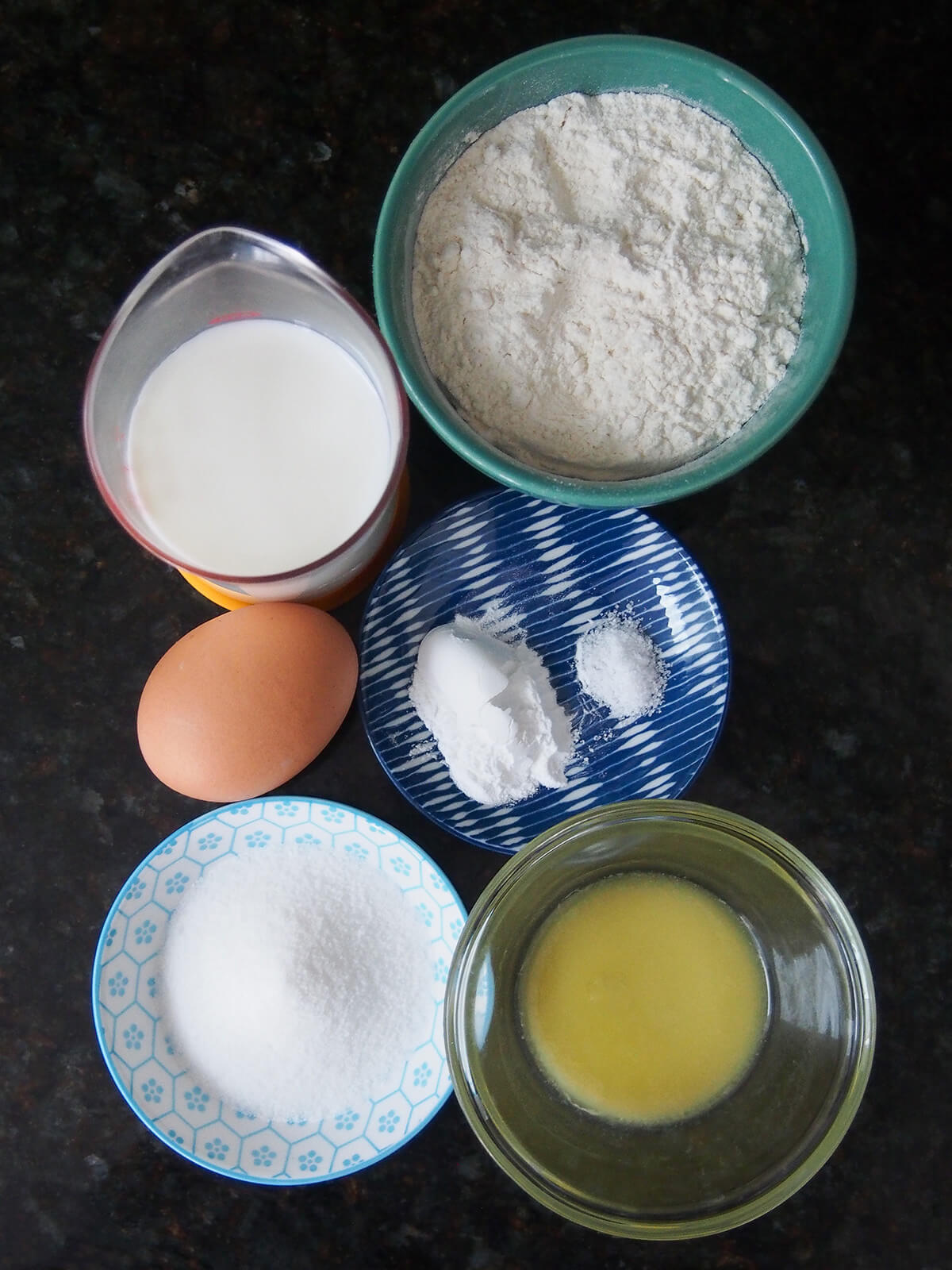 bowls of flour and sugar, measure with milk, egg, and melted butter in dish from overhead.