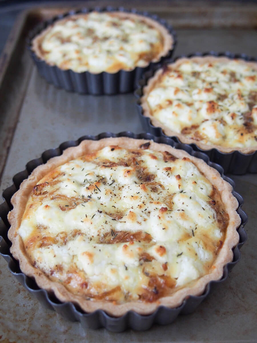 caramelized onion and goat cheese tarts on baking sheet just out oven.