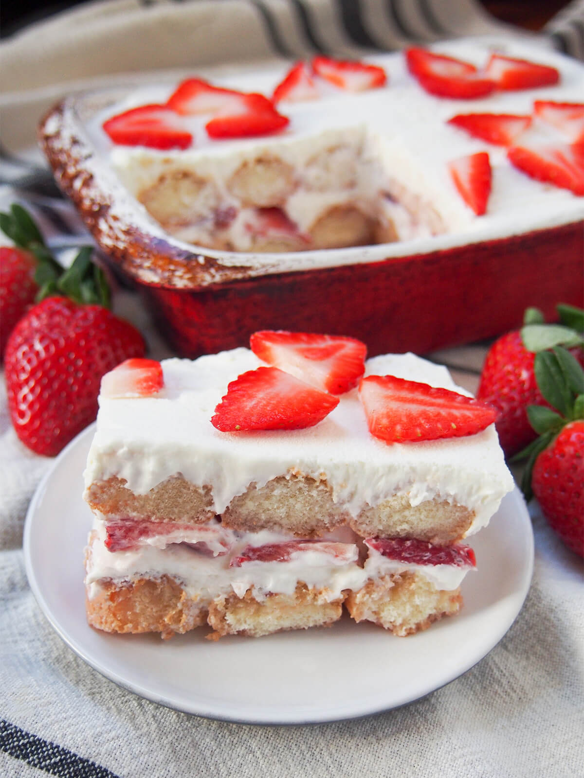 slice of strawberry tiramisu in front of dish with rest in it.