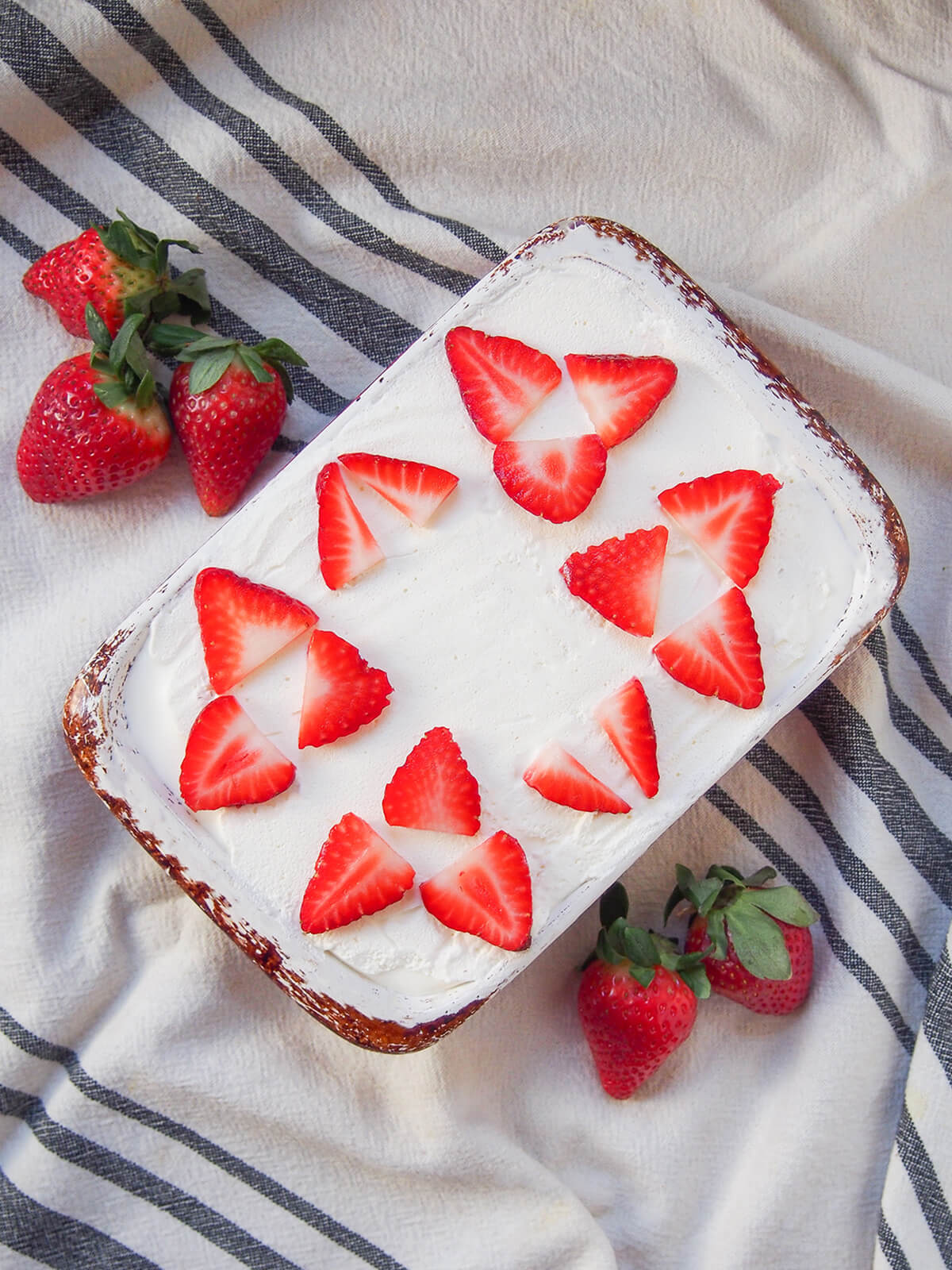 overhead view of whole strawberry tiramisu with strawberry slices decorating the cream