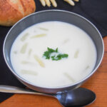 bowl of white asparagus soup with spoon below bowl.