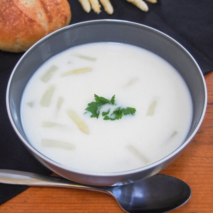 bowl of white asparagus soup with spoon below bowl.