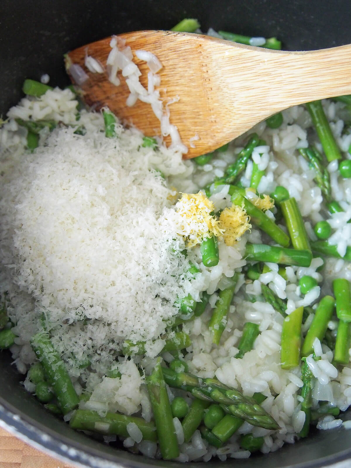 adding parmesan and lemon zest to pot with lemon asparagus risotto.