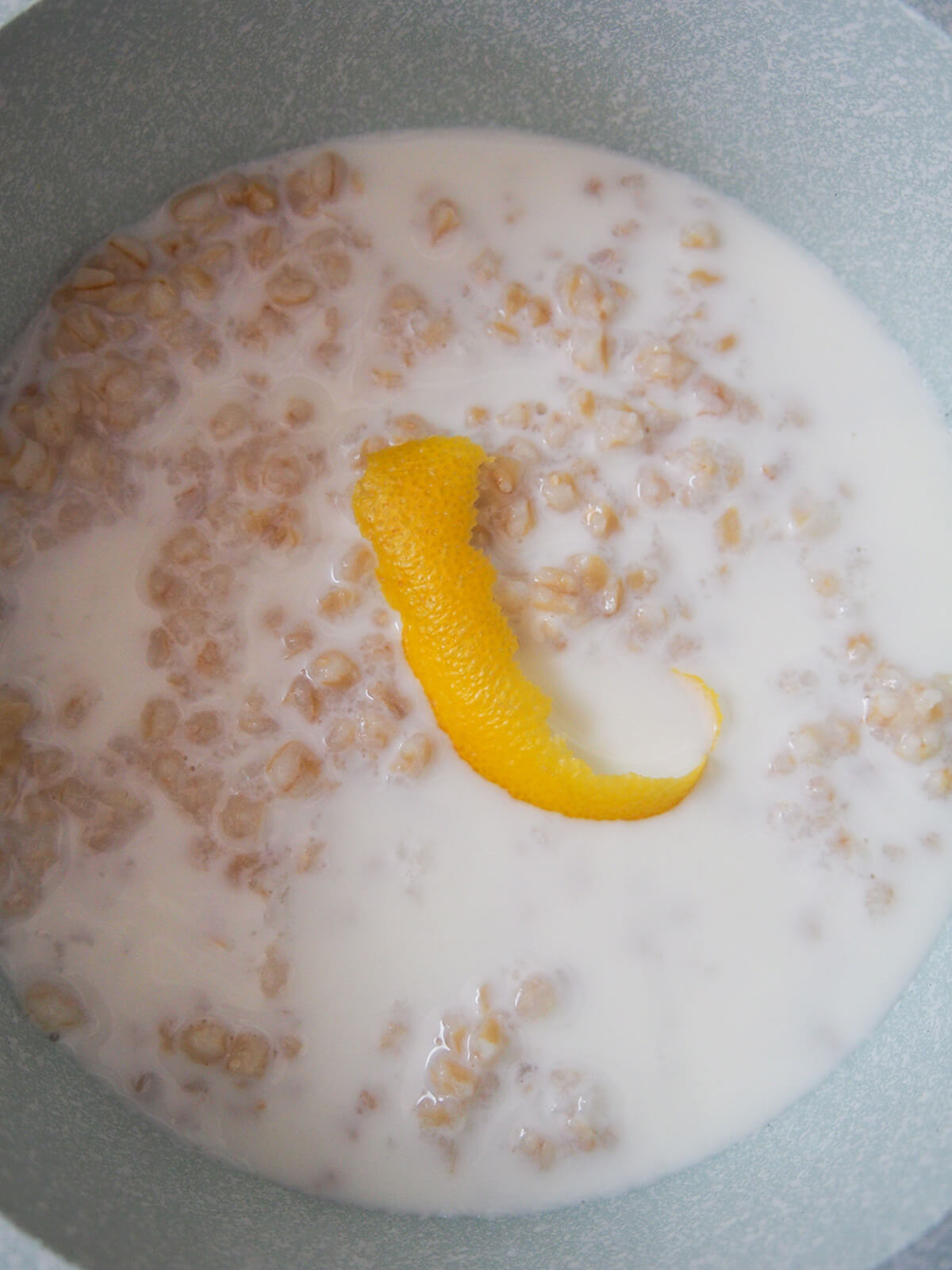 grano cotto for pastiera napoletana grano cotto, milk and lemon peel in pan before simmering.
