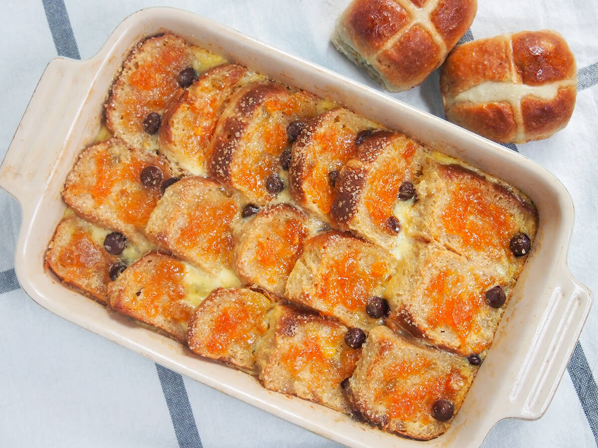 dish of hot cross bun bread and butter pudding with whole hot cross buns above dish.