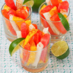 glasses of Mexican fruit cups with half lime to side.