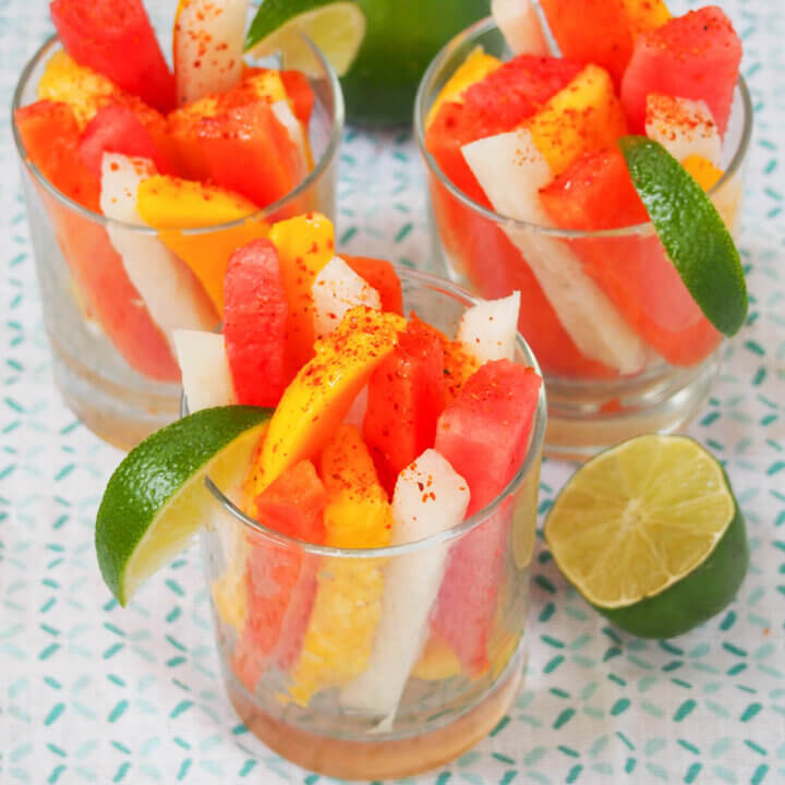 glasses of Mexican fruit cups with half lime to side.