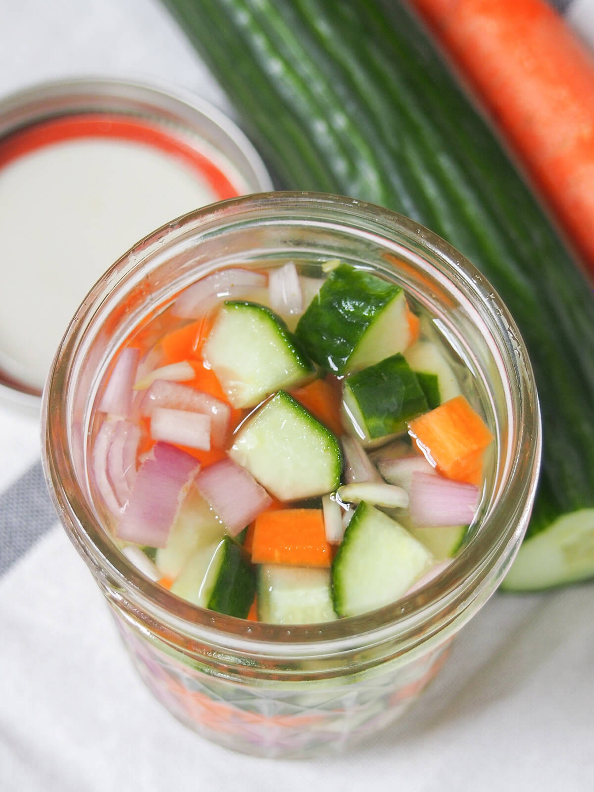 Acar timun are Indonesian pickled cucumbers, and other vegetables that are easy to make, with a great sweet-sharp flavor. Crunchy, flavorful and versatile in how you use them, too. overhead view of jar of acar timun, Indonesian pickles.
