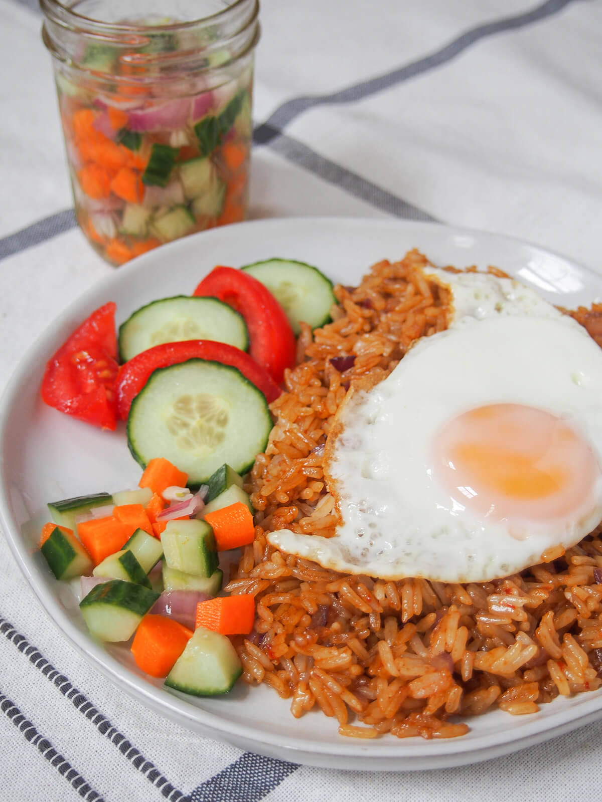 acar timun served with nasi goreng some acar timun on side of plate of nasi goreng topped with fried egg.