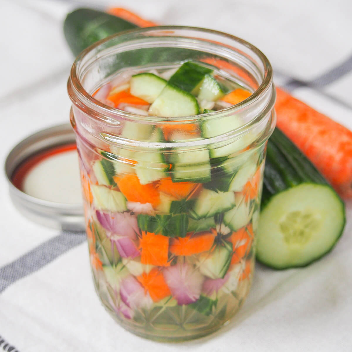Acar timun are Indonesian pickled cucumbers, and other vegetables that are easy to make, with a great sweet-sharp flavor. Crunchy, flavorful and versatile in how you use them, too. side view of jar of acar timun, Indonesian pickles.