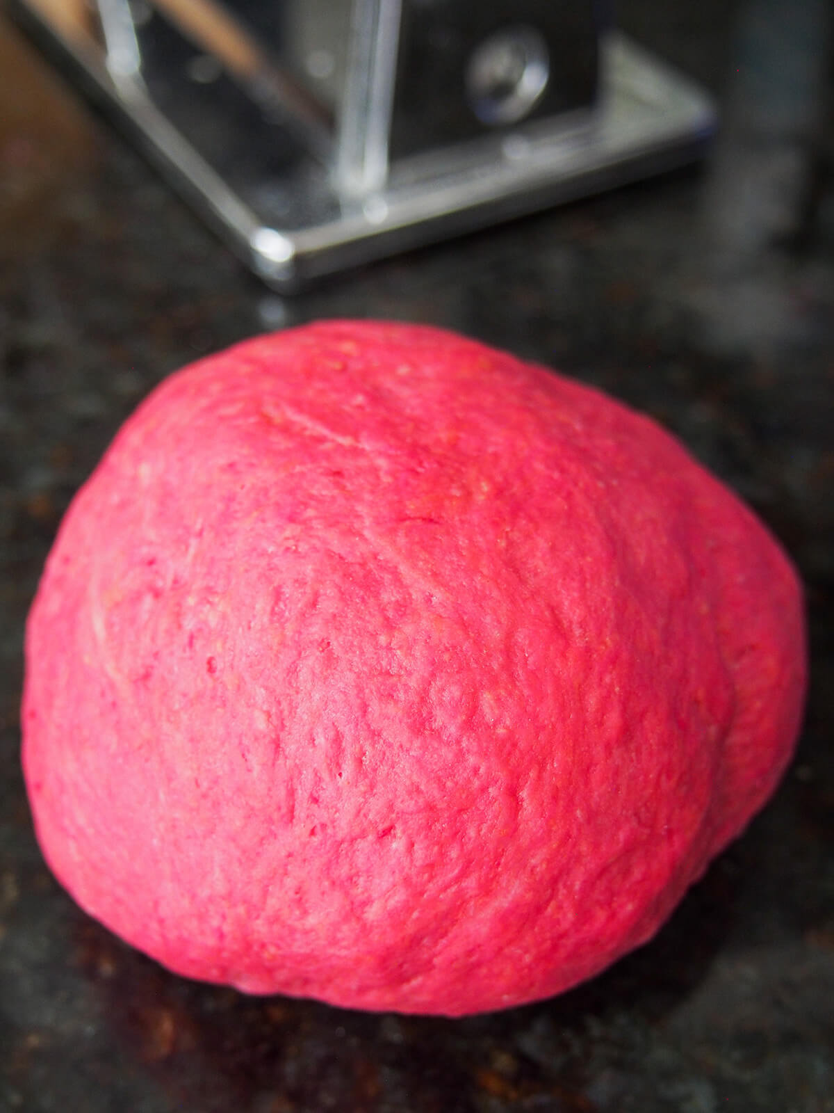 ball of beet pasta dough on work surface.