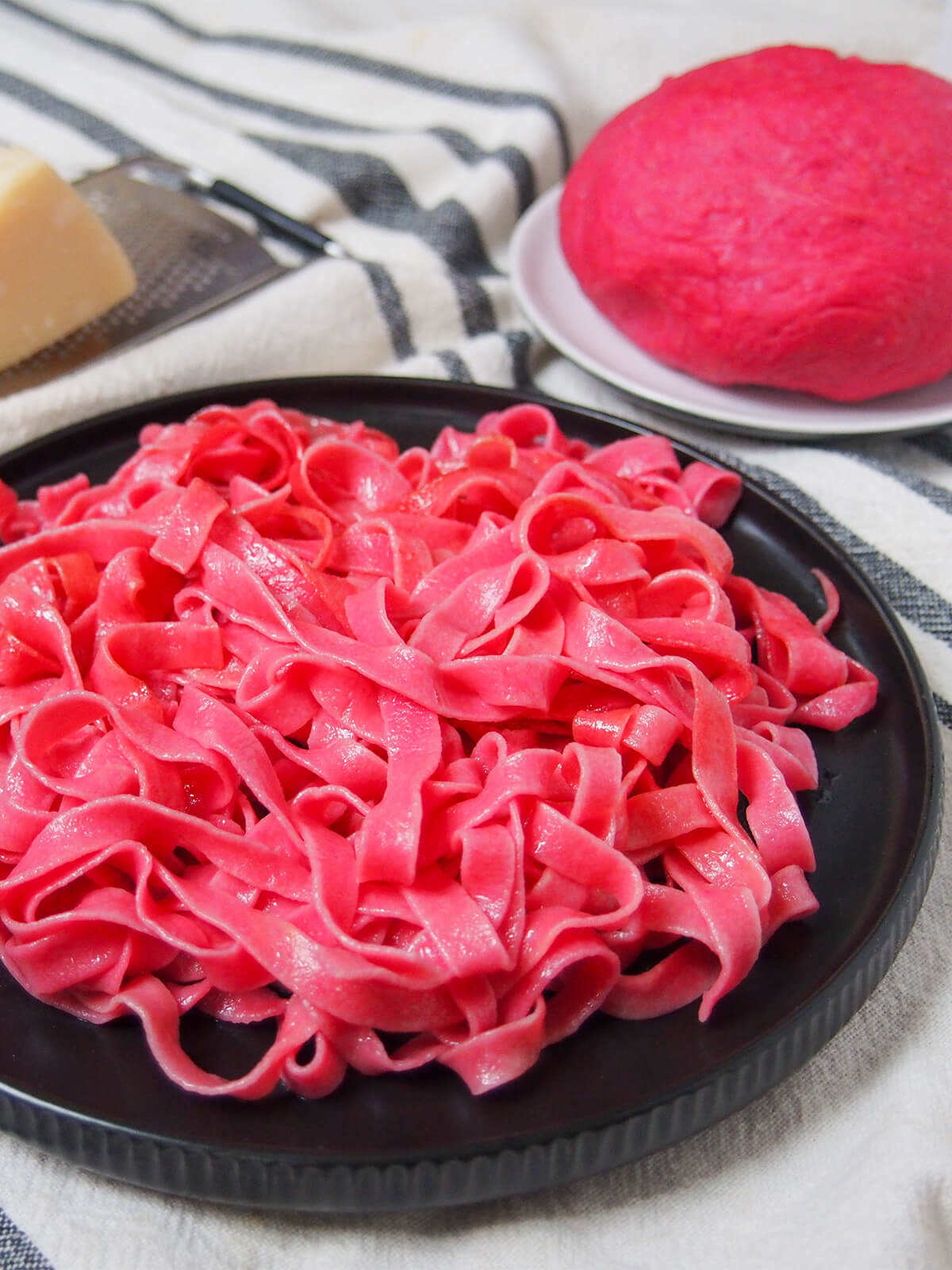 plate of beet pasta with ball of beet pasta dough behind