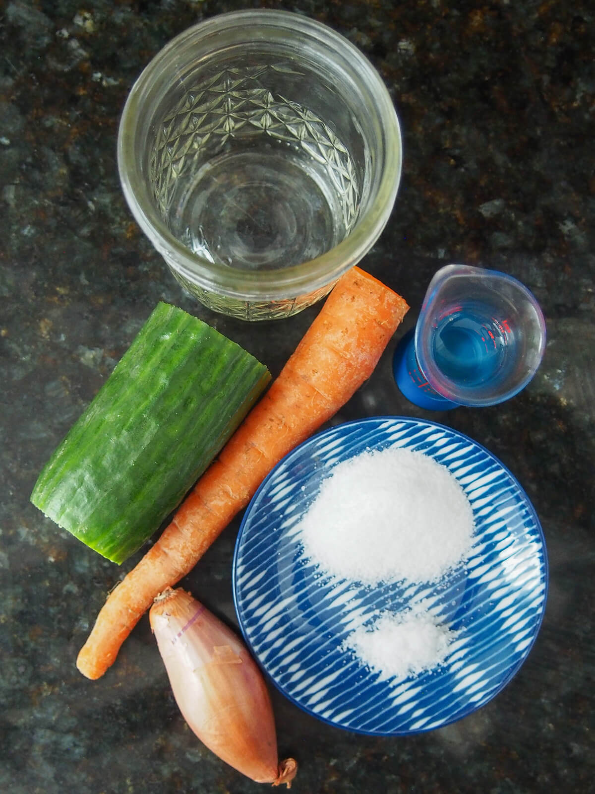 ingredients for acar timun part cucumber, carrot, shallot, jar, measure with vinegar and plate with salt and sugar.