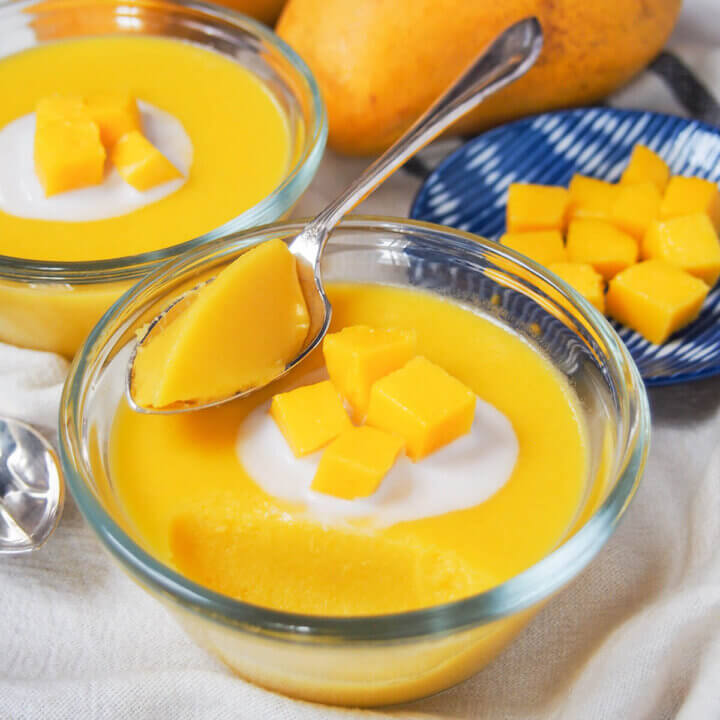 bowl of mango pudding with spoon in it towards back.
