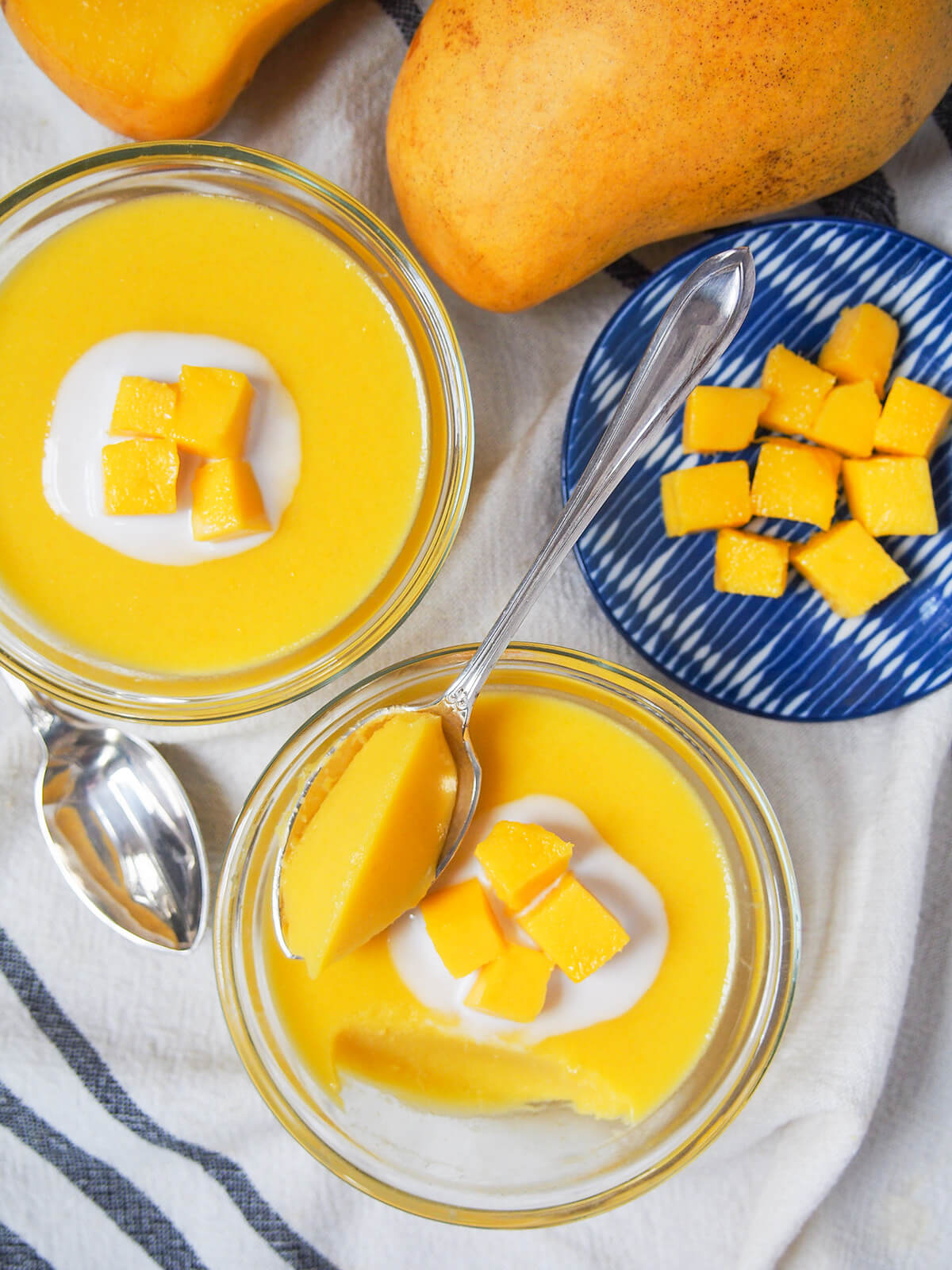 overhead view of bowls of mango pudding with one with spoonful sitting on top.