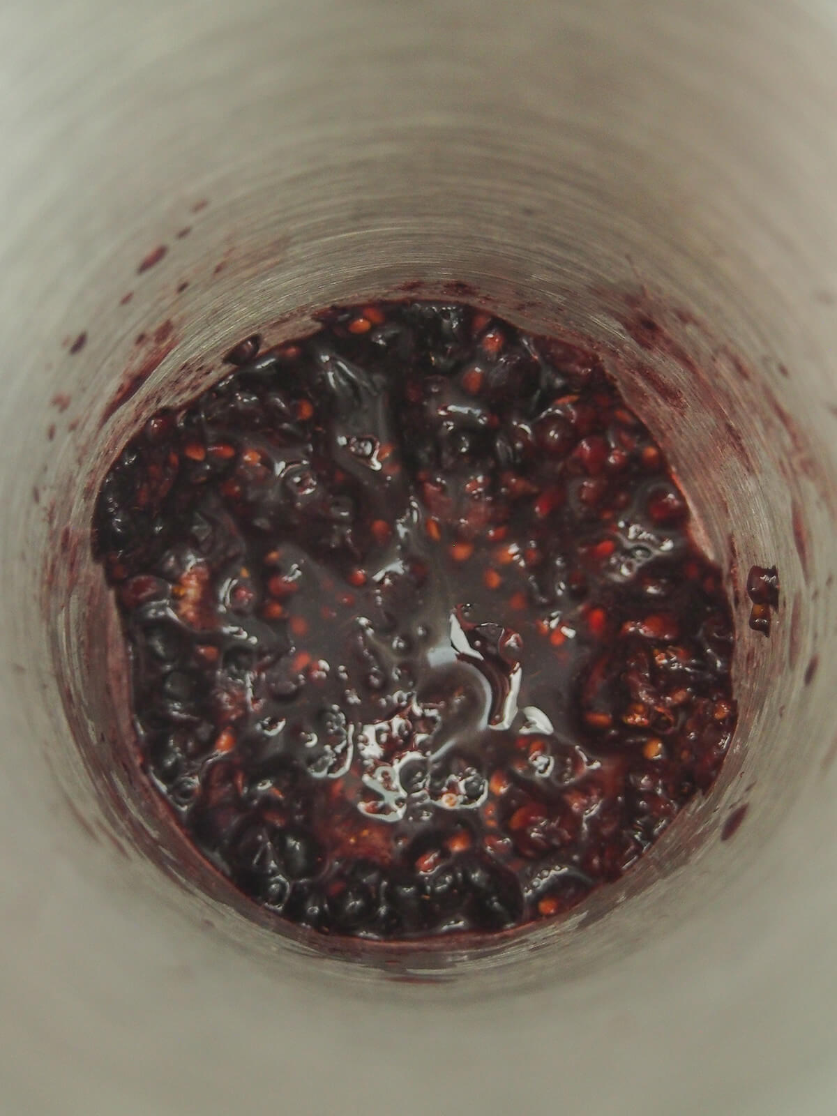 muddles blackberries in bottom of cocktail shaker.