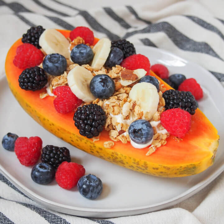 side view of a papaya boat loaded with berries and granola.
