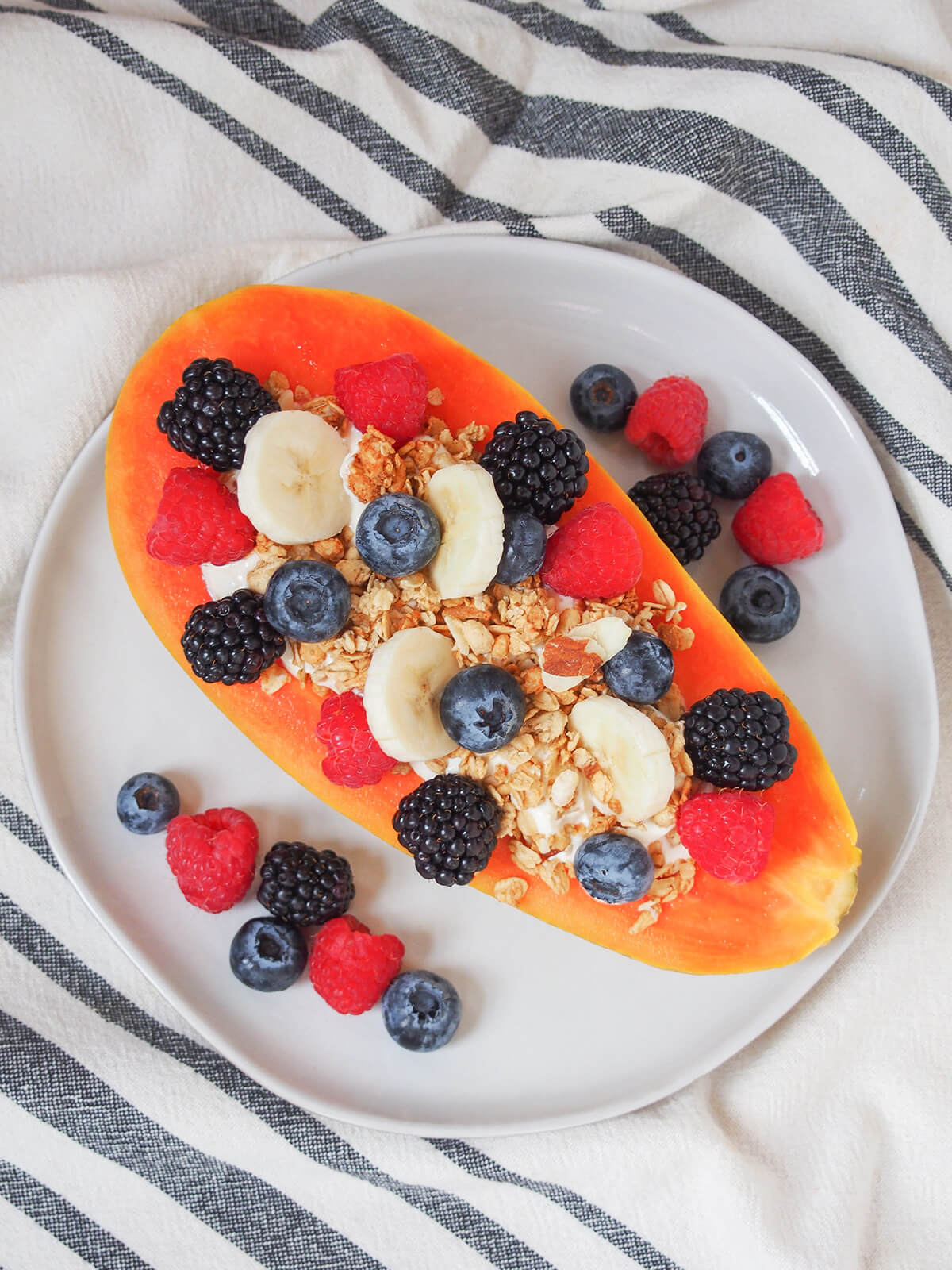 overhead view of papaya boat on plate with berries either side.