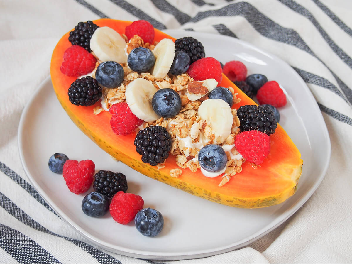 papaya boat viewed from the side with berries next to papaya.