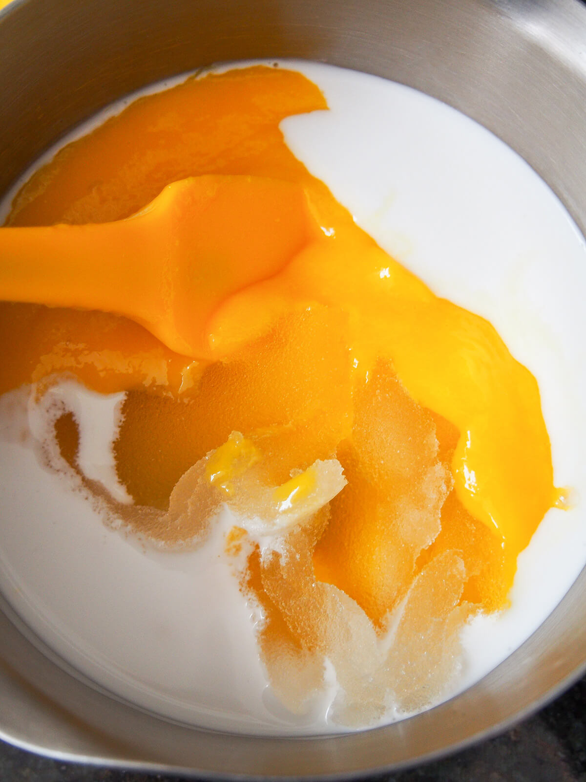 coconut milk, bloomed gelatin, sugar and mango puree in pan before mixing and warming.