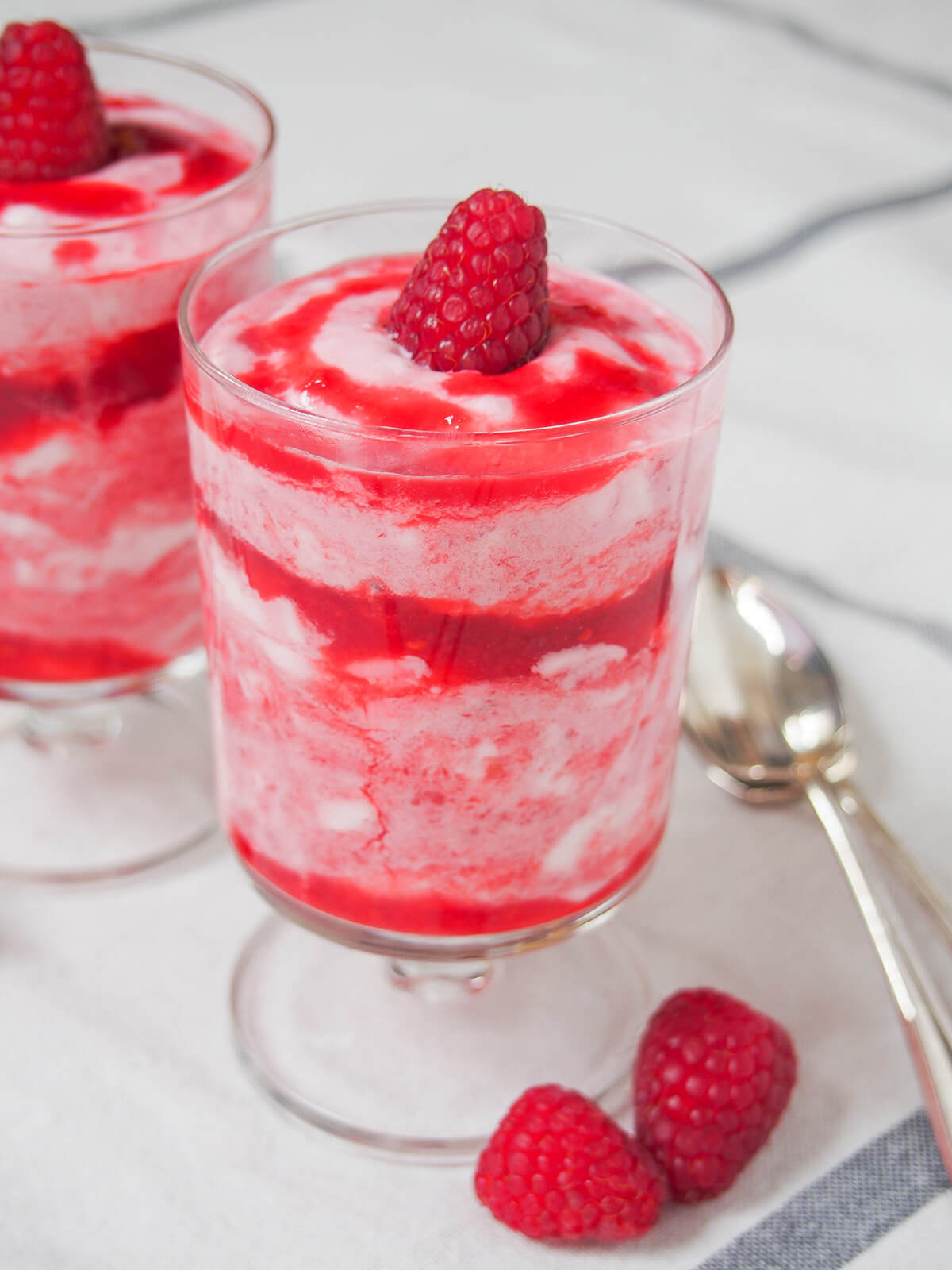 glass of raspberry fool with raspberries to side of glass.